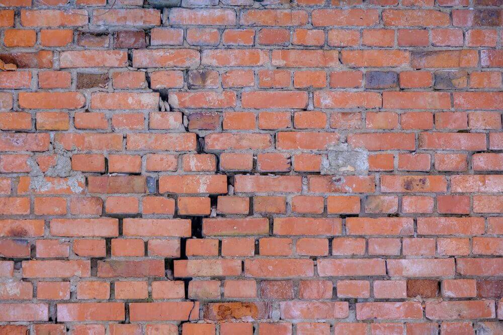 Bowing and cracked white brick wall under soil pressure